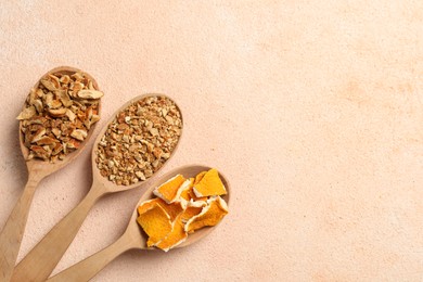 Spoons with dried orange seasoning zest and peel on beige textured table, flat lay. Space for text