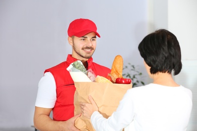 Photo of Male courier delivering food to client on light background