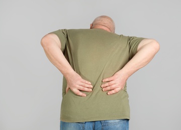 Photo of Senior man suffering from pain in back on light background