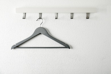 Photo of Rack with empty clothes hanger on light wall. Wardrobe accessory