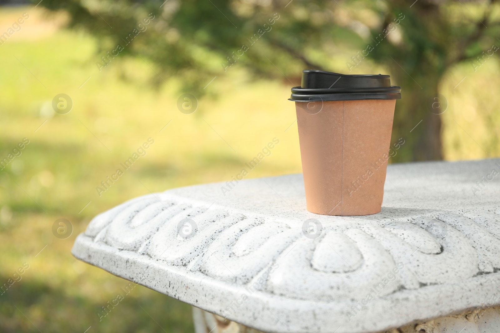 Photo of Cardboard cup with tasty coffee on stone bench outdoors. Space for text