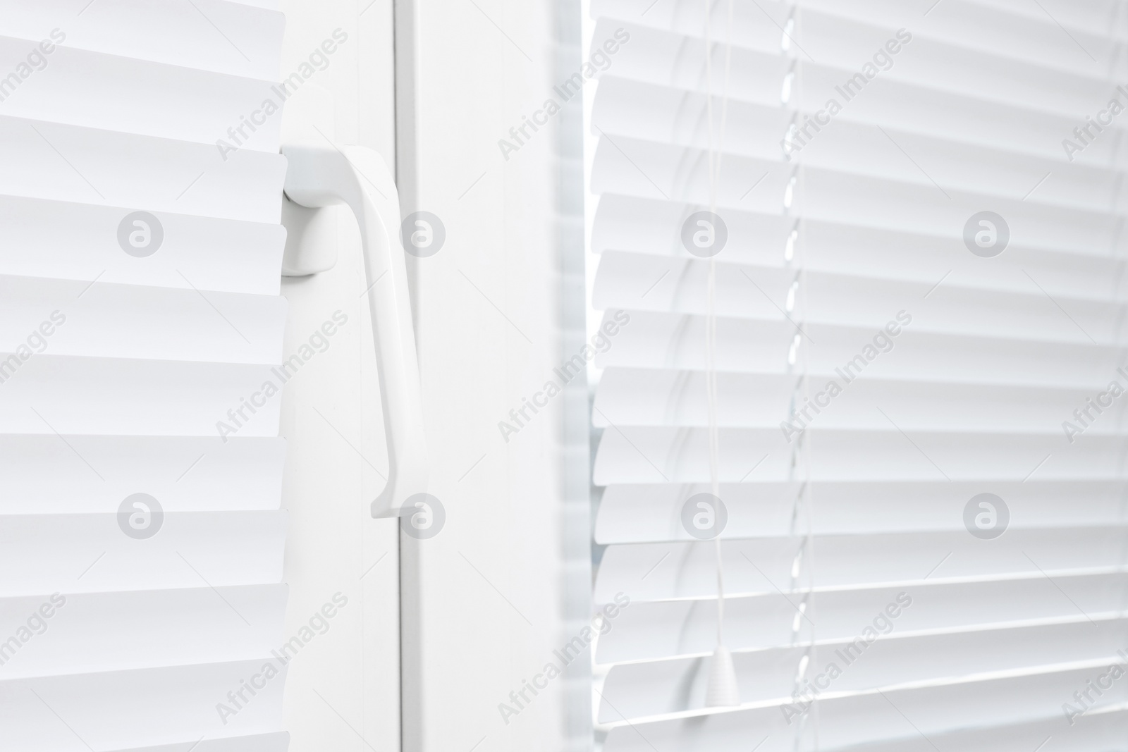 Photo of Window with closed white horizontal blinds indoors, closeup