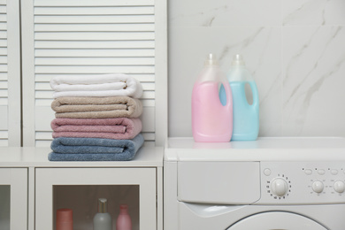 Photo of Stack of fresh towels and detergents in laundry room