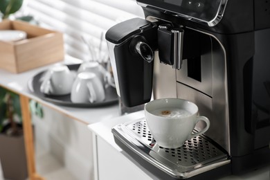 Photo of Modern coffee machine with cup of cappuccino in office. Space for text