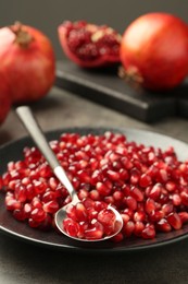 Photo of Ripe juicy pomegranate grains on grey table