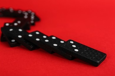 Photo of Fallen black domino tiles on red background. Space for text