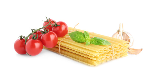 Photo of Uncooked lasagna sheets with cherry tomatoes, garlic and basil isolated on white