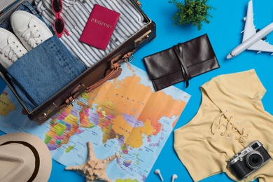 Photo of Flat lay composition with suitcase and travel accessories on light blue background. Summer vacation