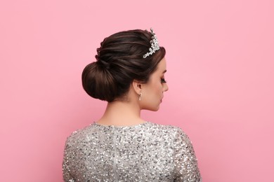 Woman wearing luxurious tiara on pink background, back view