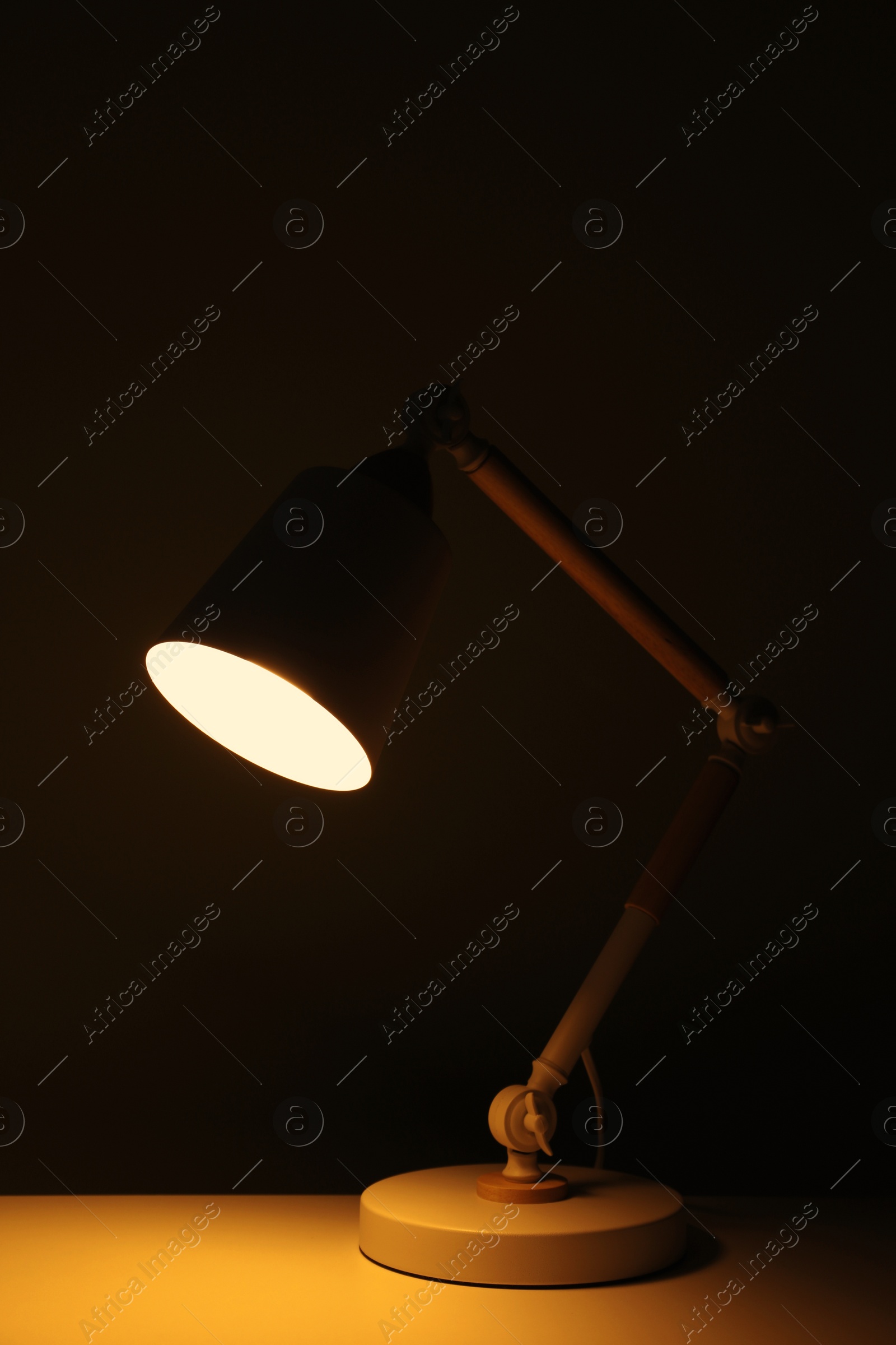 Photo of Stylish modern desk lamp on table at night