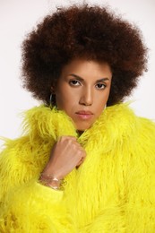 Portrait of beautiful young woman in stylish yellow fur coat on white background