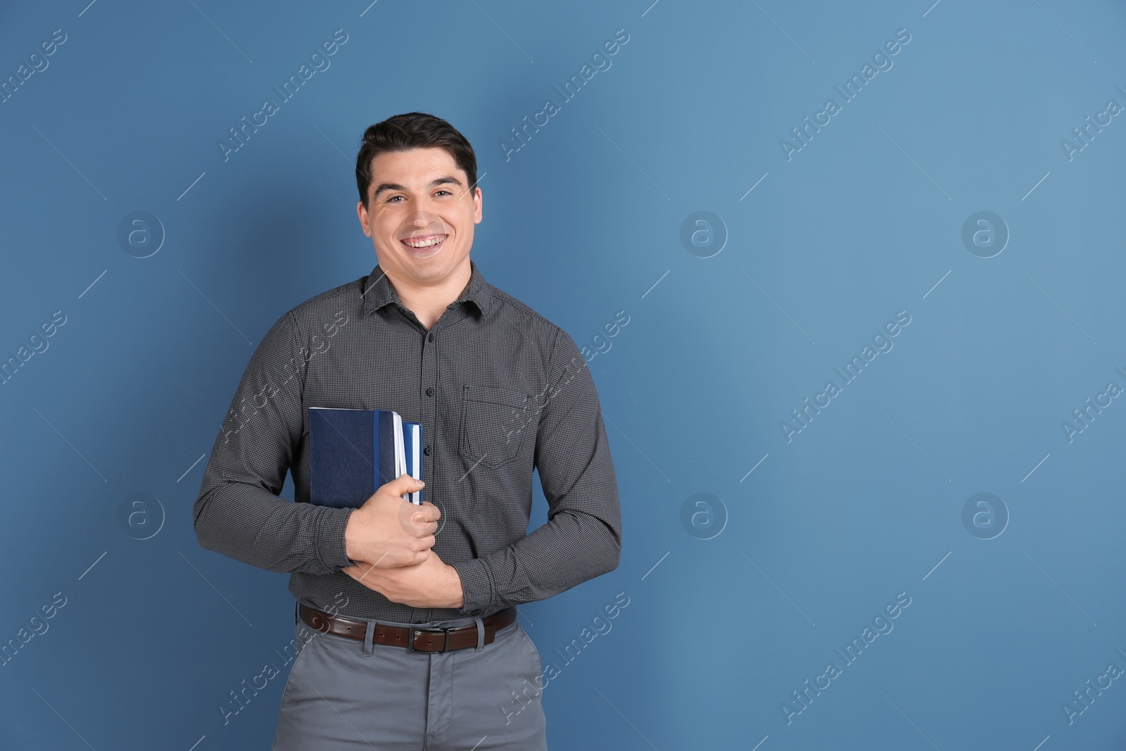 Photo of Portrait of male teacher with notebooks on color background