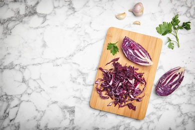 Photo of Wooden board with chopped red cabbage on table, top view