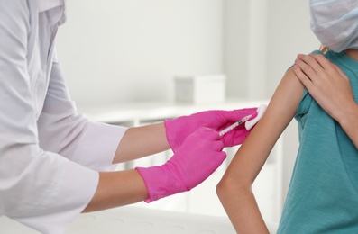 Doctor vaccinating little girl in hospital, closeup. Health care