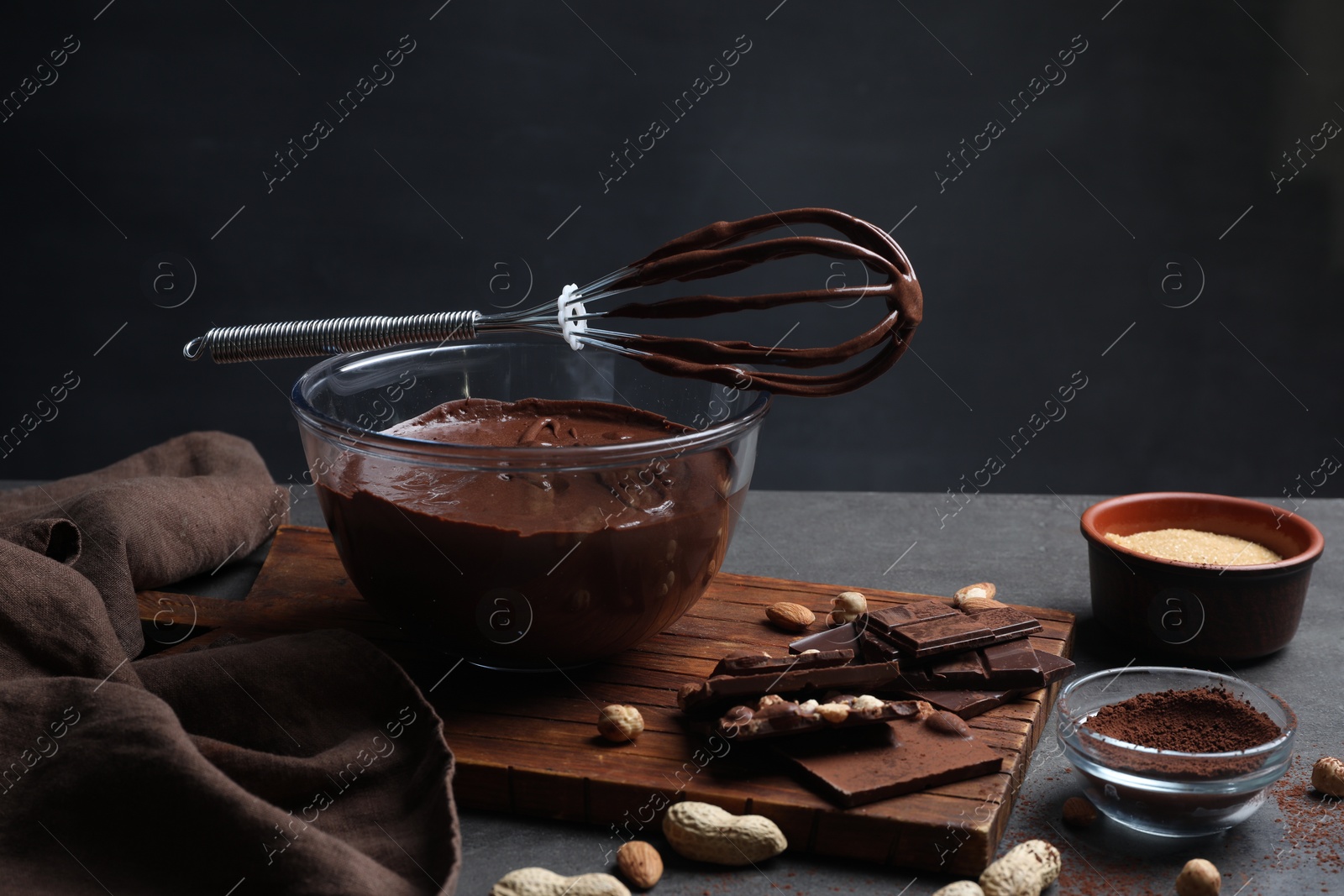 Photo of Bowl of chocolate cream, whisk and ingredients on gray table