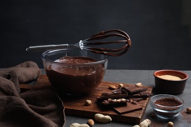 Bowl of chocolate cream, whisk and ingredients on gray table