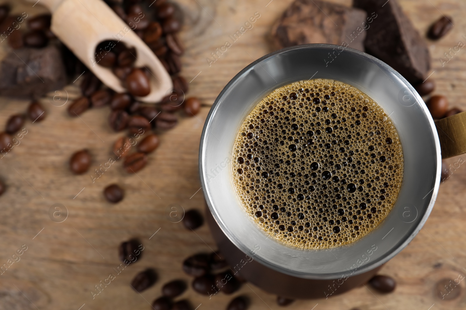 Photo of Turkish coffee pot with hot drink and beans on wooden table, flat lay. Space for text