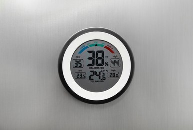 Photo of Round digital hygrometer with thermometer on metal surface