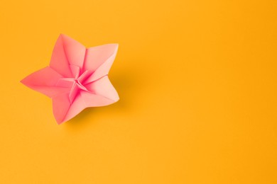 Photo of Origami art. Handmade pink paper flower on yellow background, top view with space for text