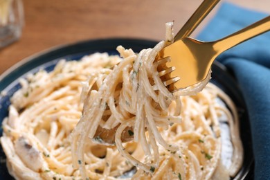 Photo of Eating delicious pasta with mushroom sauce at table, closeup