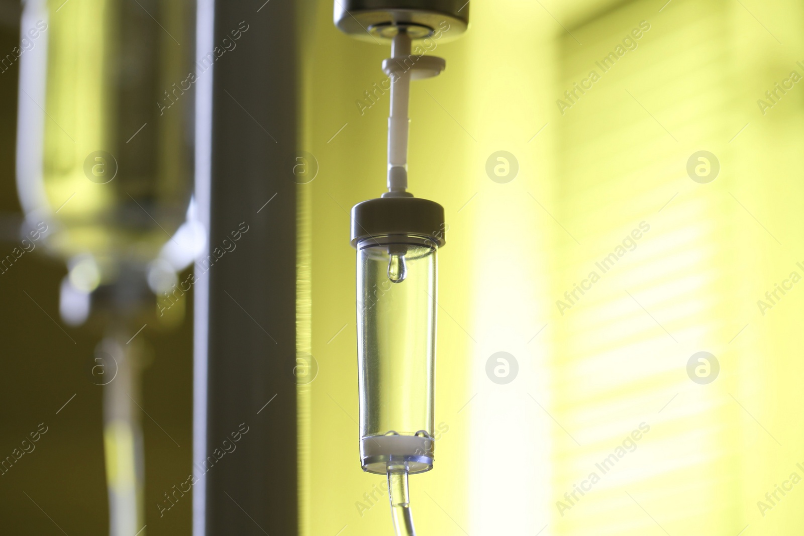 Photo of IV drip chamber against blurred yellow background