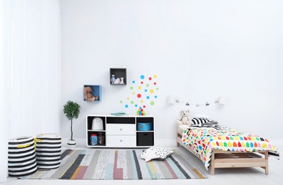 Photo of Modern child room interior with comfortable bed and striped carpet. Space for text