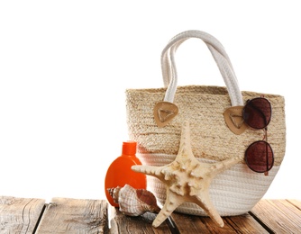 Photo of Stylish bag with beach accessories on wooden table