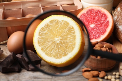 Different products with magnifier focused on lemon, closeup. Food allergy concept