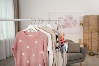 Photo of Wardrobe rack with stylish warm clothes indoors. Space for text