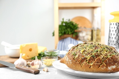 Photo of Tasty homemade garlic bread with cheese and herbs on grey table in kitchen. Space for text