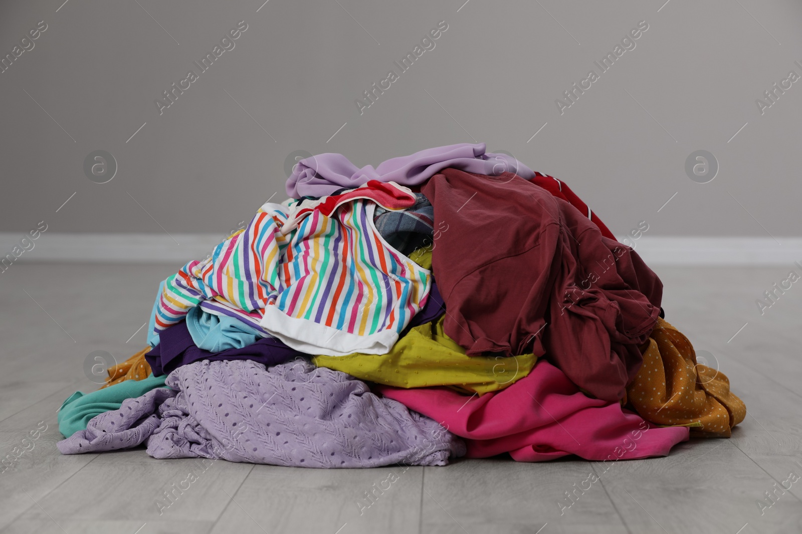 Photo of Pile of dirty clothes on floor near grey wall indoors