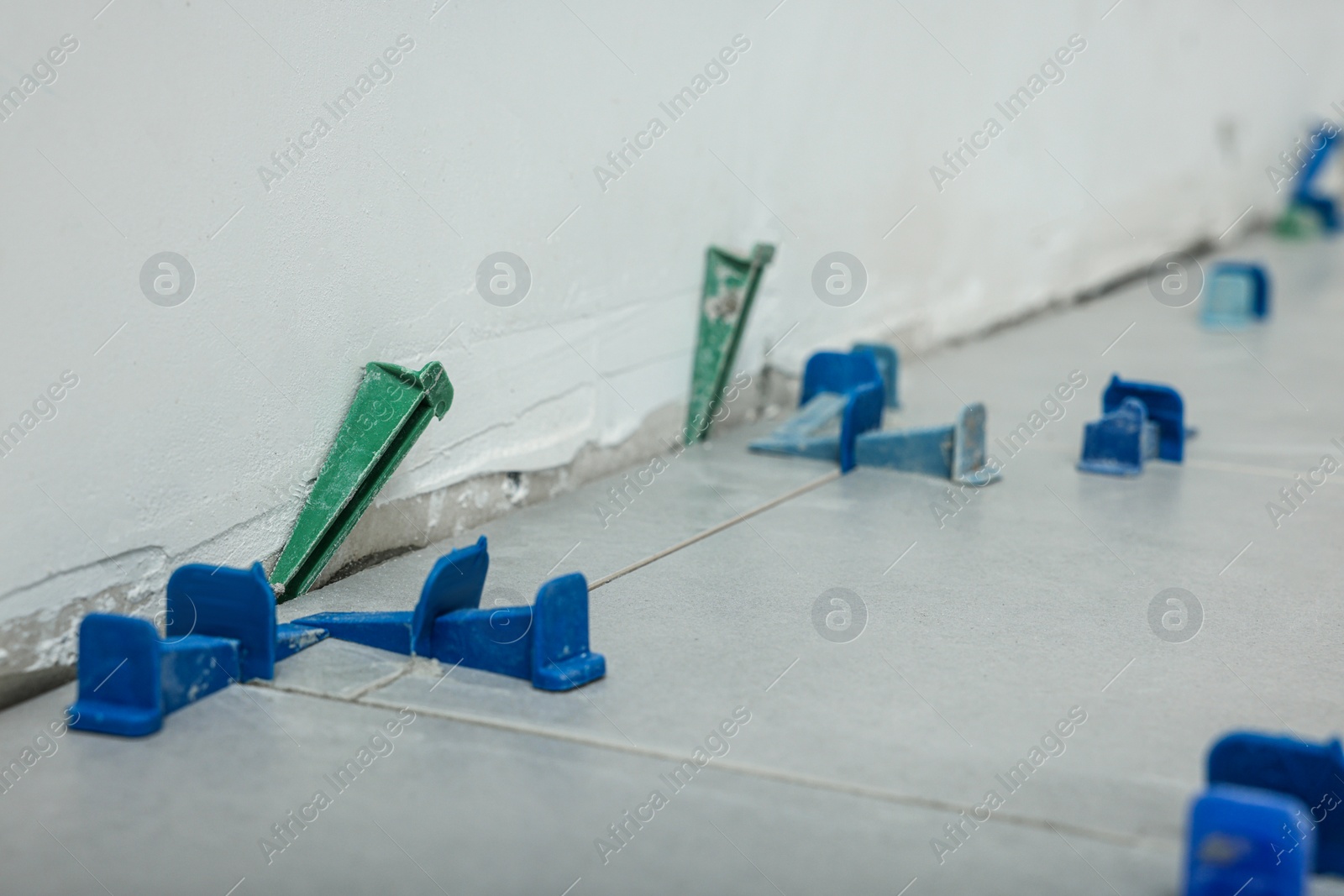 Photo of Beautiful tiles with colorful wedges on floor near wall, closeup