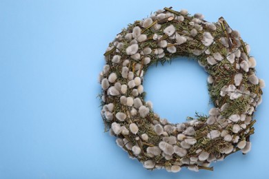 Wreath made of beautiful willow flowers on light blue background, top view. Space for text