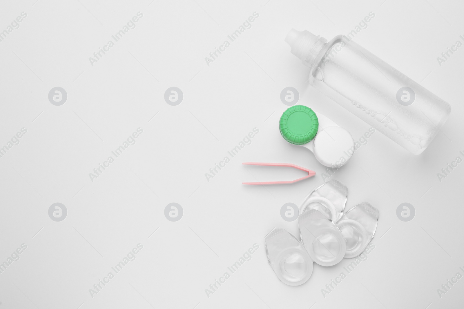 Photo of Packages with contact lenses, case, tweezers and drops on white background, flat lay. Space for text