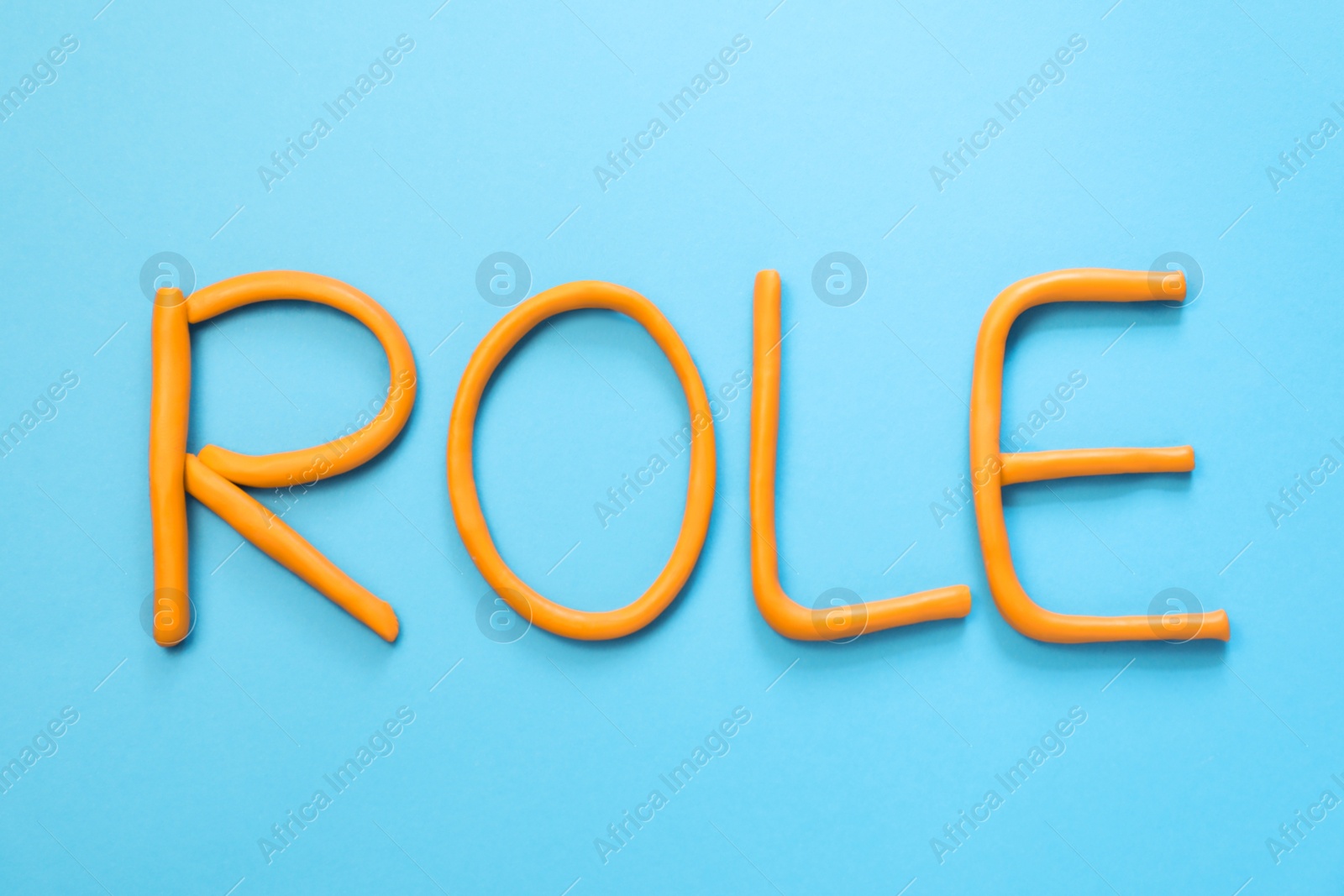 Photo of Word Role made with orange plasticine on light blue background, flat lay