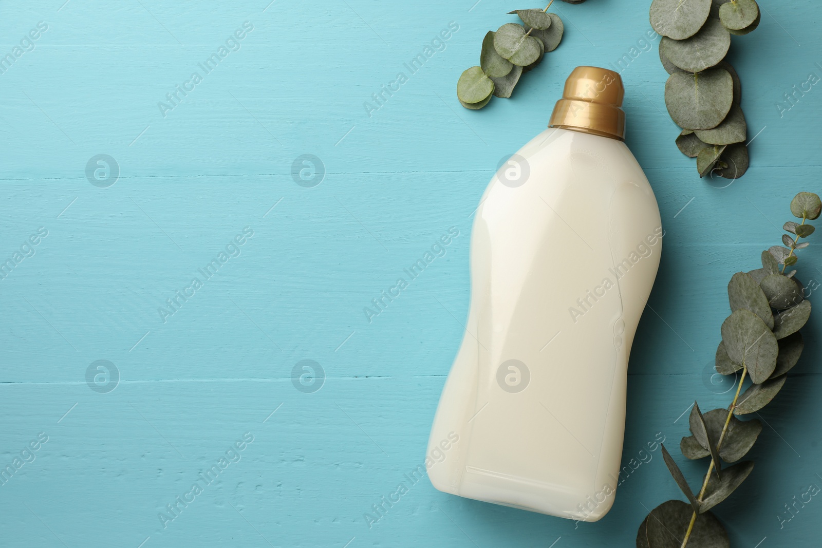 Bottle of fabric softener and eucalyptus leaves on light blue wooden table, flat lay. Space for text Photo of Bottle of fabric softener and eucalyptus leaves on light blue wooden table, flat lay. Space for text