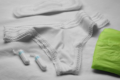 Photo of Woman's panties, menstrual pads and tampons on white fabric