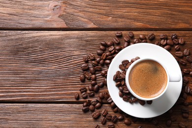 Cup of hot aromatic coffee and roasted beans on wooden table, flat lay. Space for text