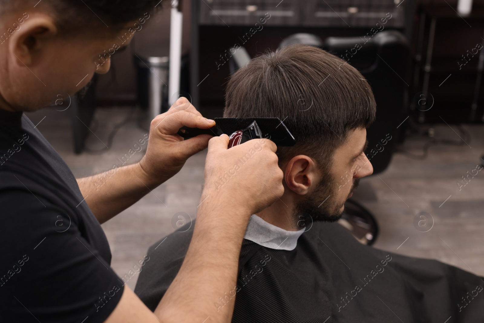 Photo of Professional hairdresser making stylish haircut in barbershop