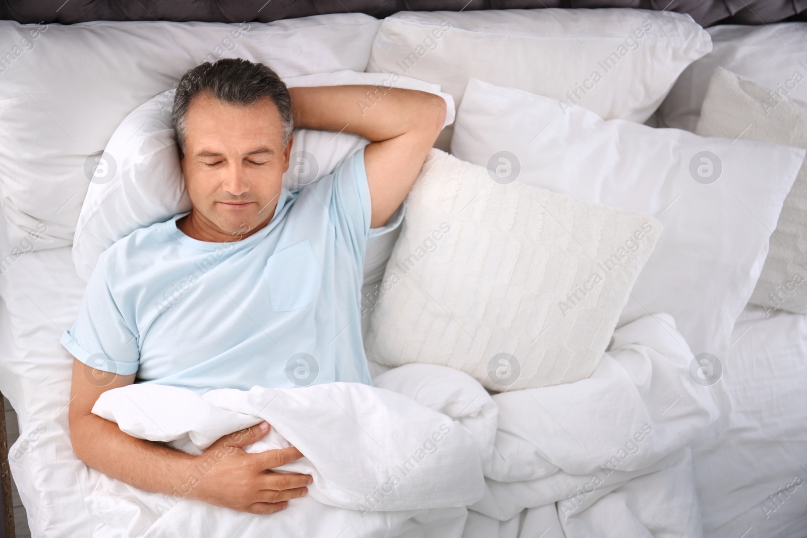 Photo of Man sleeping on comfortable pillow in bed at home, top view