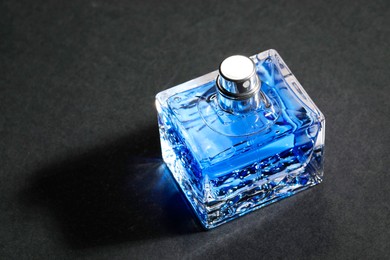 Photo of Blue men's perfume in bottle on black background, space for text