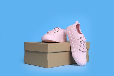 Photo of Pair of comfortable sports shoes and box on turquoise background