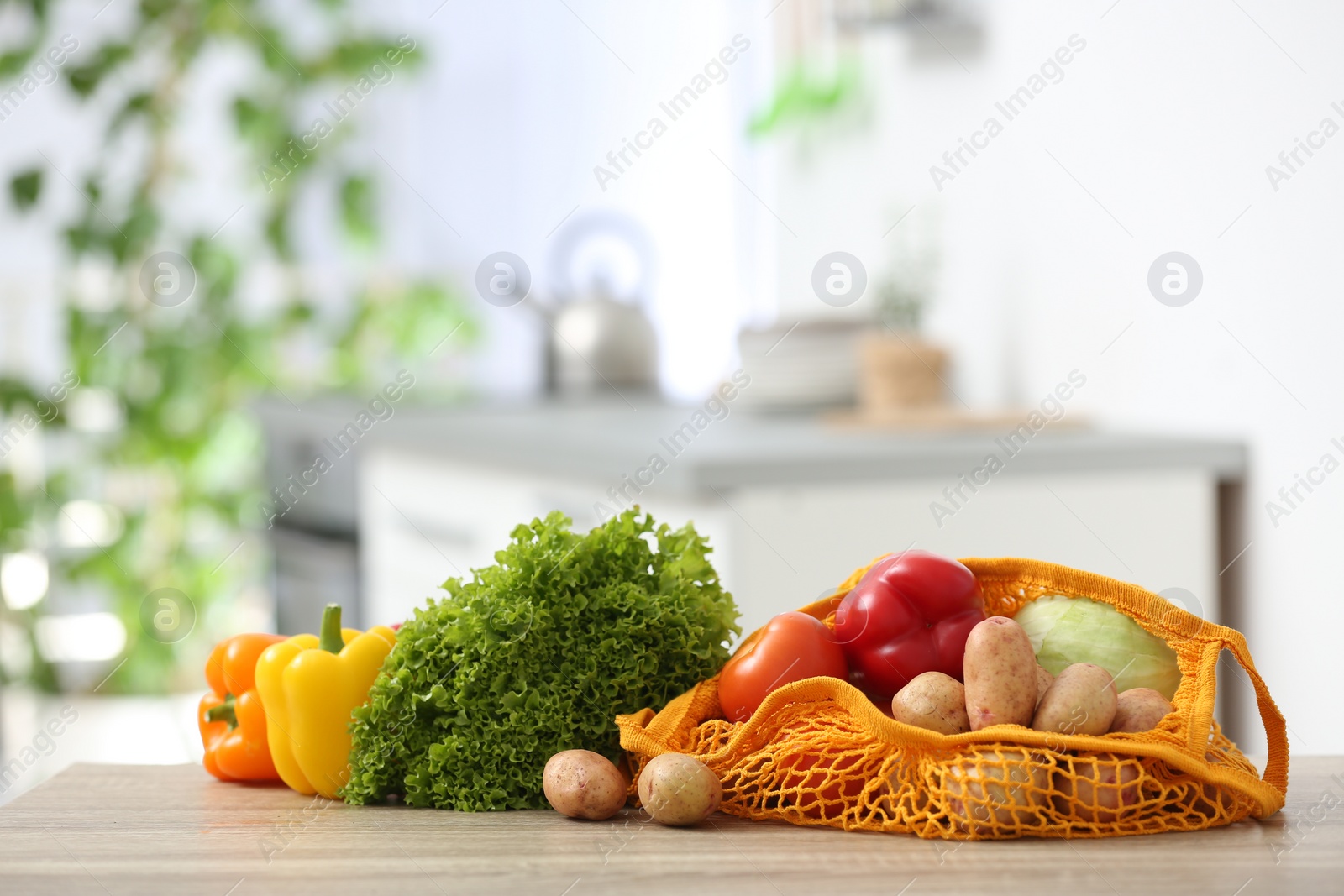 Photo of Net bags with vegetables on wooden table in kitchen