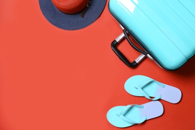 Photo of Suitcase and beach accessories on red background, flat lay. Space for text