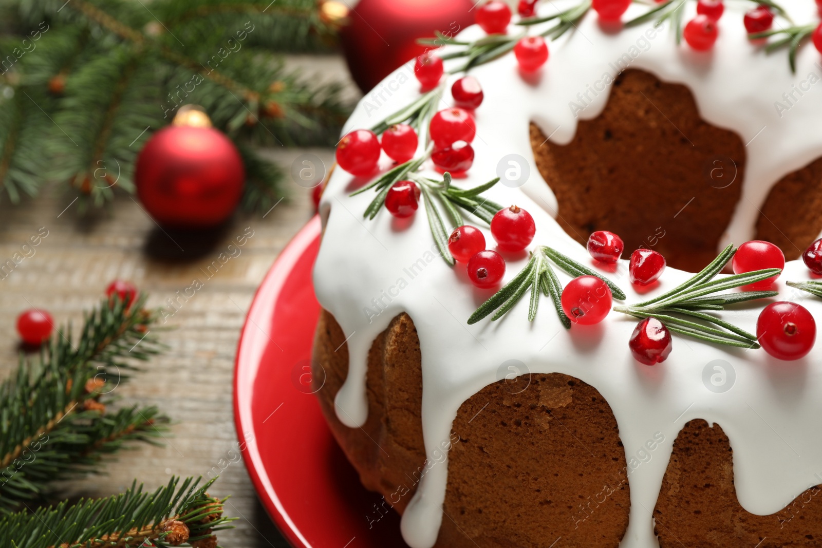 Photo of Traditional Christmas cake decorated with glaze, pomegranate seeds, cranberries and rosemary on table, closeup