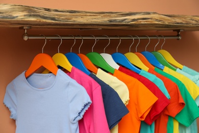 Photo of Rack with different child's clothes near coral wall, closeup