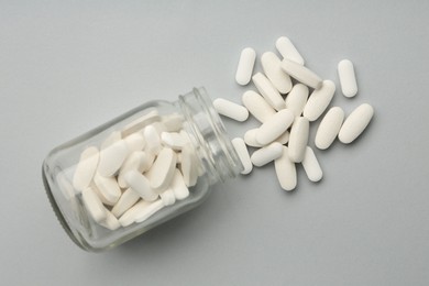 Photo of Vitamin pills and bottle on grey background, top view