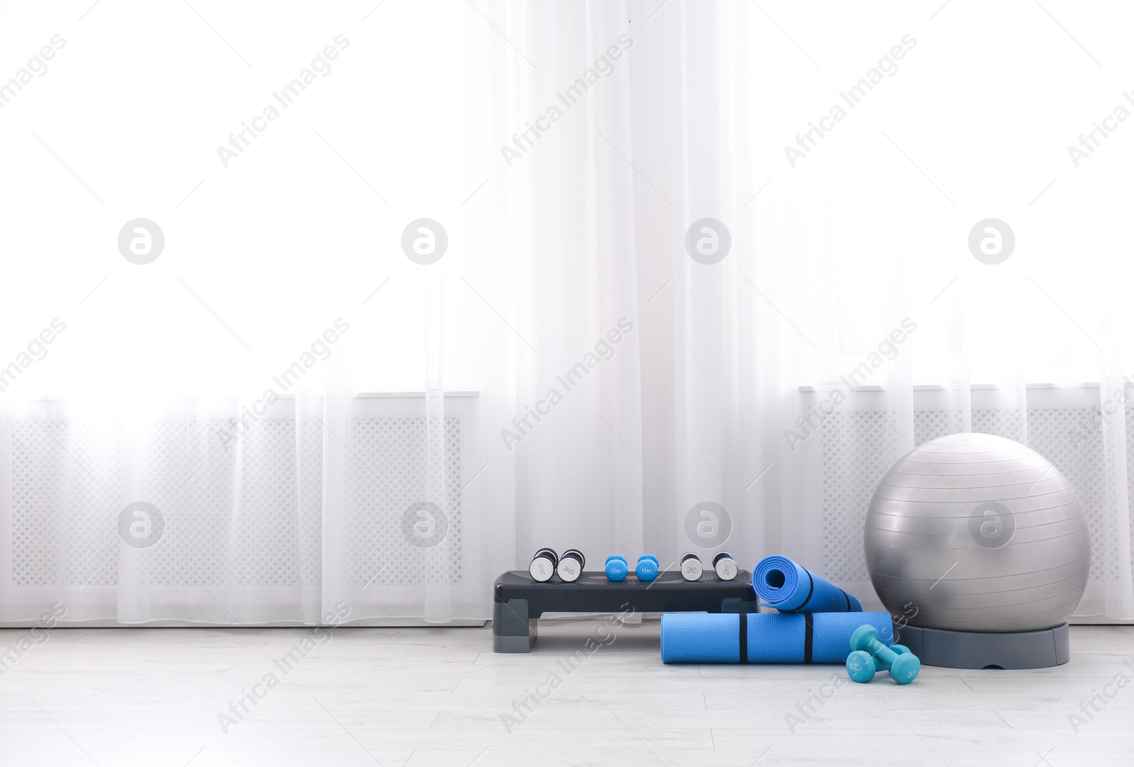 Photo of Different sports equipment near window in gym. Space for text