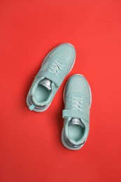 Pair of comfortable sports shoes on red background, flat lay