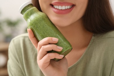 Woman with bottle of delicious smoothie, closeup
